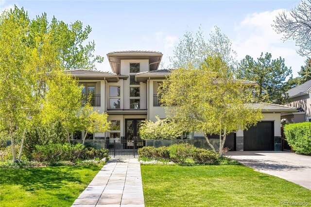 prairie-style house with driveway, stucco siding, a garage, and a front yard