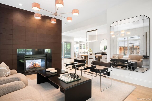 living room featuring light wood-style floors, a multi sided fireplace, and baseboards