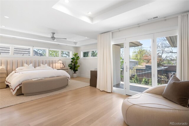 bedroom with a raised ceiling, access to exterior, recessed lighting, and light wood finished floors