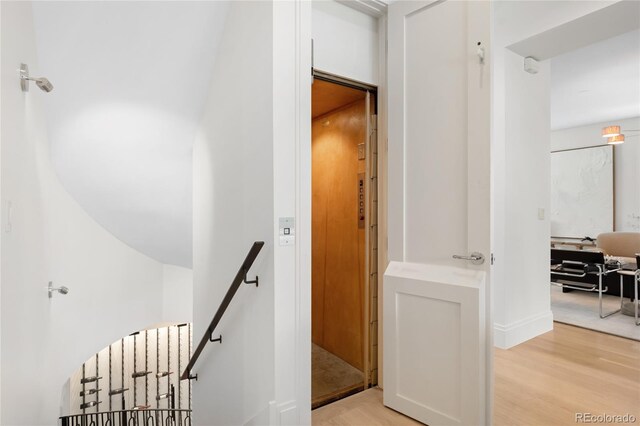 hall featuring an upstairs landing and light wood-style flooring