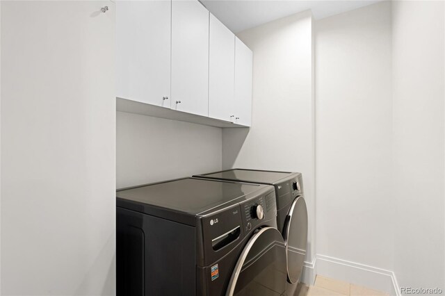 laundry room featuring washer and dryer, cabinet space, light tile patterned floors, and baseboards