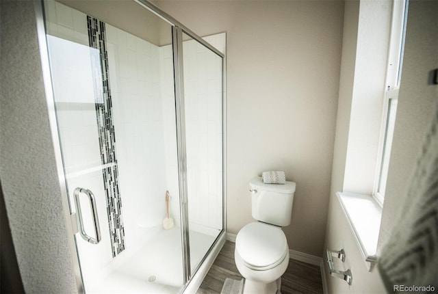 bathroom featuring hardwood / wood-style flooring, toilet, and a shower with shower door