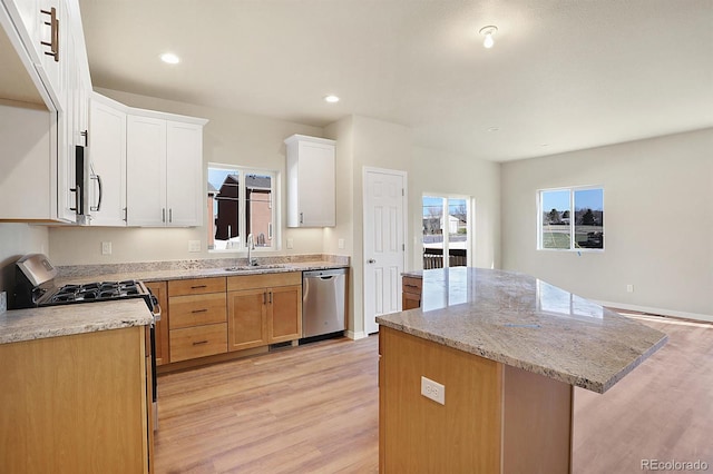 kitchen featuring a kitchen island, sink, dishwasher, light hardwood / wood-style floors, and white cabinetry