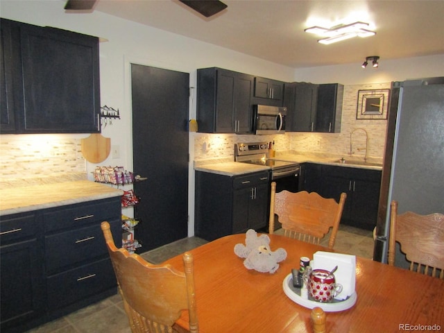 kitchen with light tile patterned floors, stainless steel appliances, tasteful backsplash, and sink