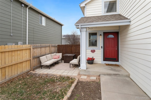 property entrance featuring a patio, an outdoor living space, fence, and a shingled roof