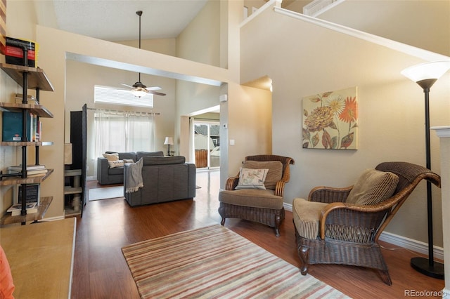 living area featuring baseboards, high vaulted ceiling, wood finished floors, and a ceiling fan