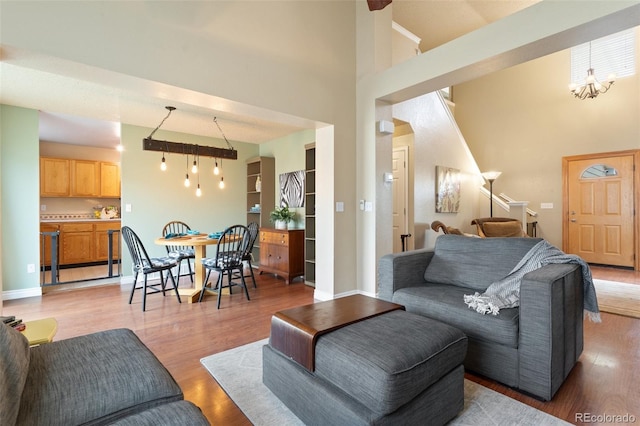 living area featuring a high ceiling, light wood-style flooring, and baseboards