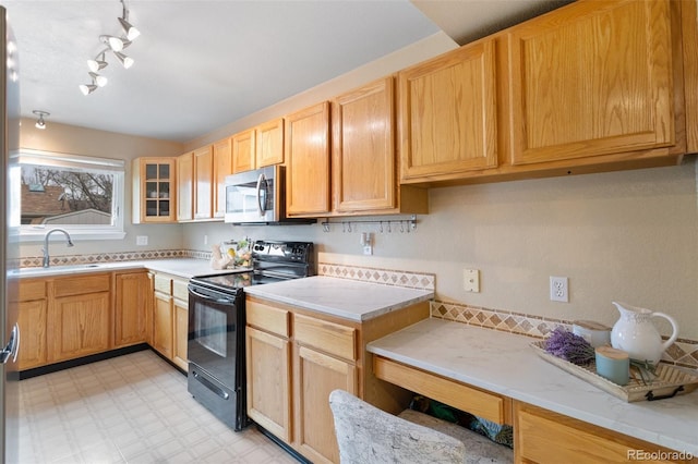 kitchen with light floors, light brown cabinetry, a sink, black electric range, and stainless steel microwave