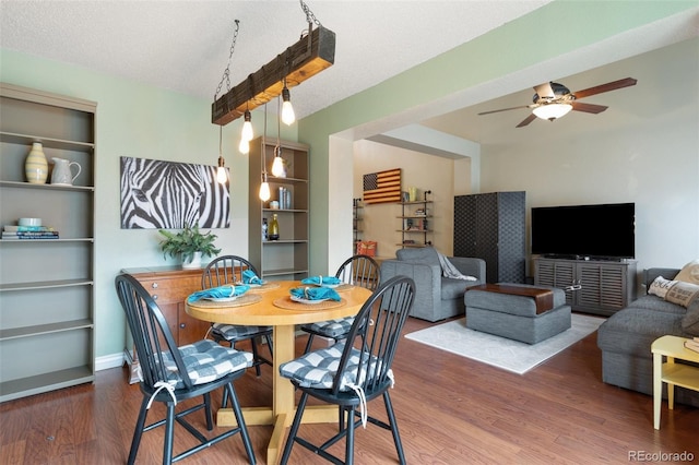 dining space with ceiling fan, baseboards, a textured ceiling, and wood finished floors