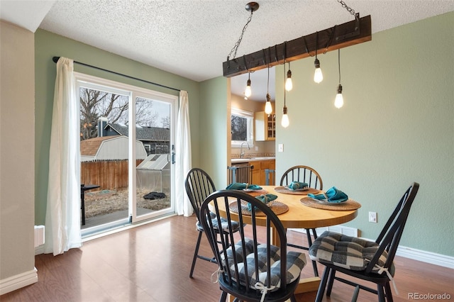 dining area featuring dark wood-type flooring, baseboards, and a textured ceiling