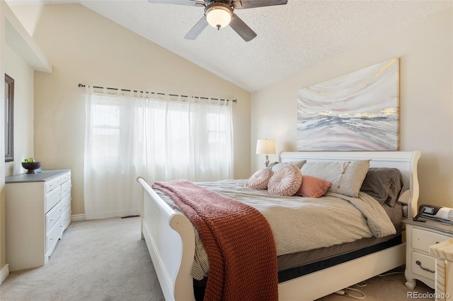 bedroom with lofted ceiling, a textured ceiling, light carpet, and a ceiling fan