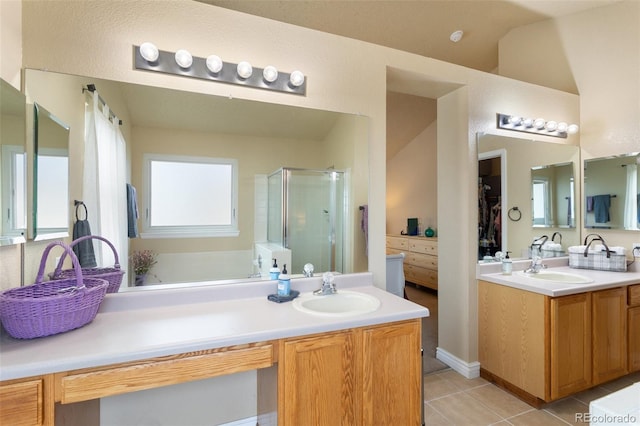 bathroom featuring tile patterned floors, a shower stall, two vanities, and a sink