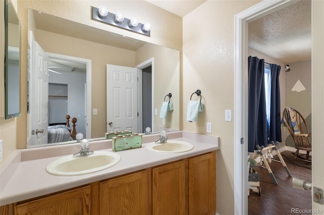 ensuite bathroom featuring a textured ceiling, ensuite bath, double vanity, and a sink