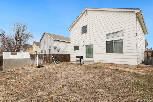 back of house featuring a greenhouse, a patio, an outbuilding, and a fenced backyard