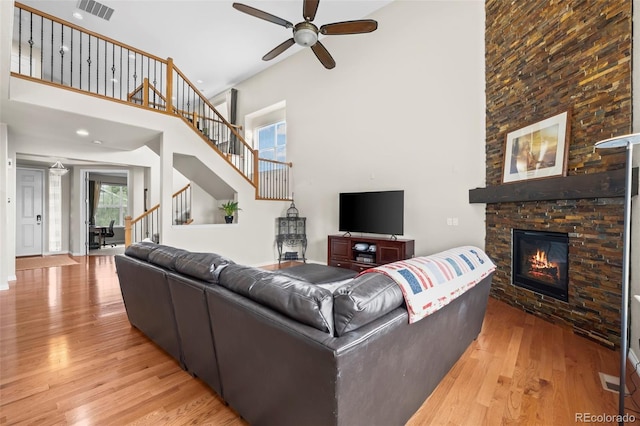 9957 Quintero St, Commerce City, CO 80022 - living room featuring light wood-style flooring, stairs, a high ceiling, ceiling fan, and a fireplace