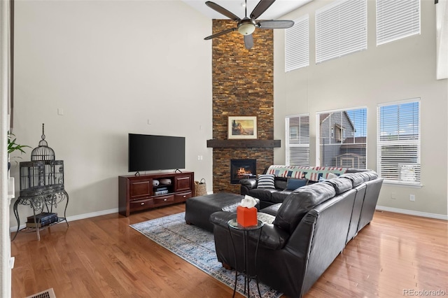 9957 Quintero St, Commerce City, CO 80022 - living room featuring a ceiling fan, a high ceiling, wood finished floors, and a stone fireplace