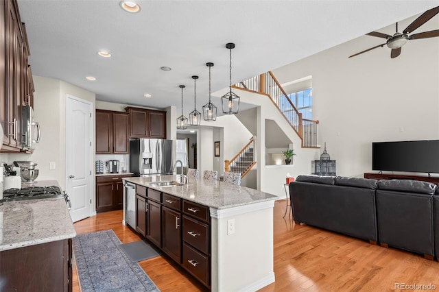 9957 Quintero St, Commerce City, CO 80022 - kitchen with stainless steel appliances, a ceiling fan, open floor plan, light wood finished floors, and decorative light fixtures