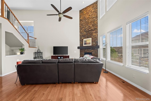 9957 Quintero St, Commerce City, CO 80022 - living room with a towering ceiling, ceiling fan, light wood-type flooring, and a stone fireplace