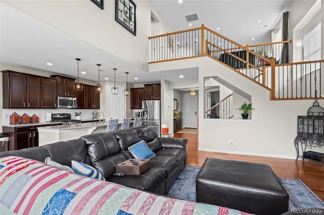 9957 Quintero St, Commerce City, CO 80022 - living room with light wood-type flooring, recessed lighting, stairs, and a towering ceiling