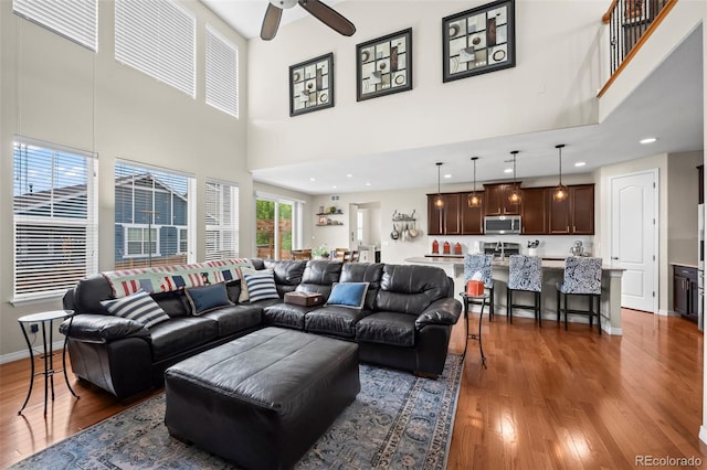 9957 Quintero St, Commerce City, CO 80022 - living room featuring a towering ceiling, wood finished floors, ceiling fan, and recessed lighting