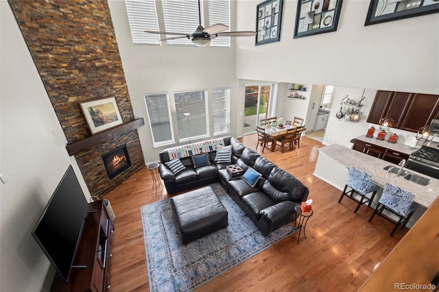 9957 Quintero St, Commerce City, CO 80022 - living area with a towering ceiling, a fireplace, wood finished floors, and a ceiling fan