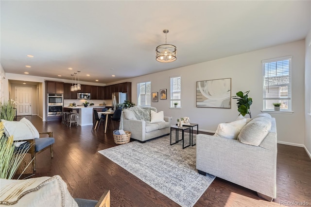 living room with dark wood-type flooring and an inviting chandelier