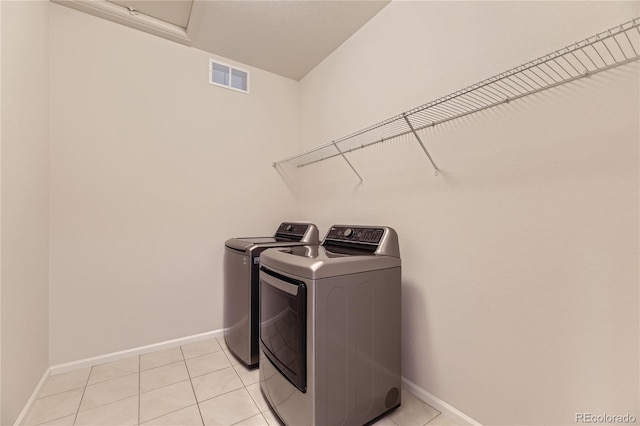 laundry area featuring washing machine and clothes dryer and light tile patterned floors