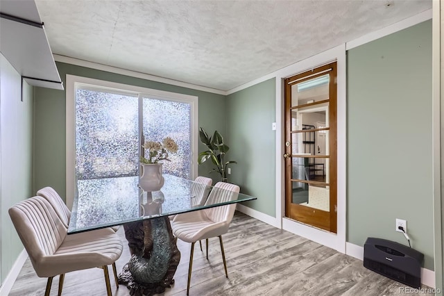 dining room featuring light hardwood / wood-style floors, a textured ceiling, and ornamental molding