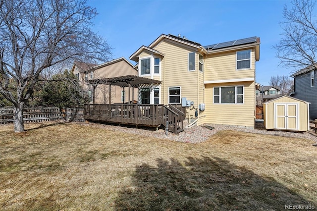 back of property featuring a storage shed, a pergola, a yard, a wooden deck, and solar panels