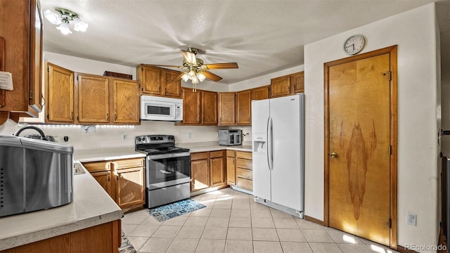 3102 Pine Cone Ct, Grand Junction, CO 81504 - kitchen with white appliances, light countertops, brown cabinets, light tile patterned floors, and a textured ceiling