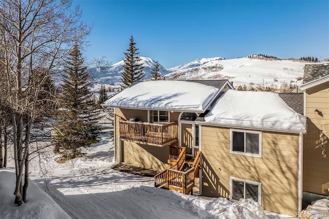 snow covered rear of property featuring a mountain view