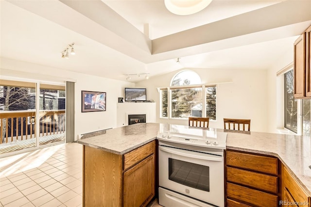 kitchen featuring light tile patterned floors, track lighting, white electric stove, kitchen peninsula, and light stone countertops