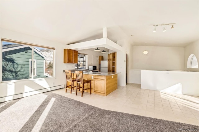 kitchen with a baseboard heating unit, vaulted ceiling, a breakfast bar, and light colored carpet