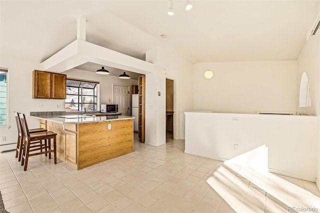 kitchen with a breakfast bar area, refrigerator, vaulted ceiling, light tile patterned flooring, and a baseboard radiator