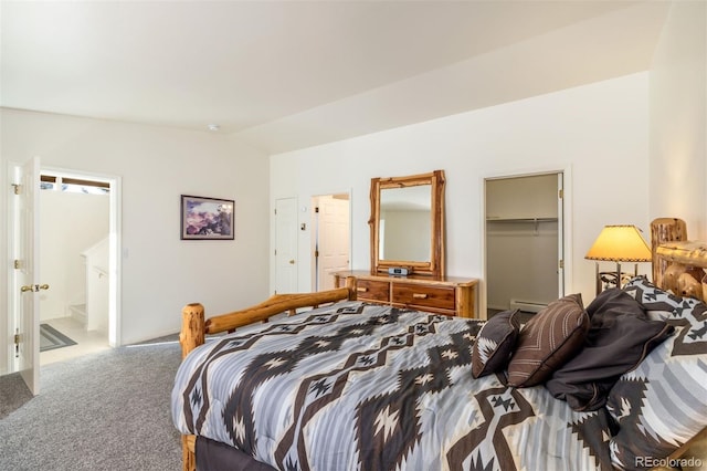 carpeted bedroom featuring lofted ceiling, ensuite bath, a spacious closet, a baseboard radiator, and a closet