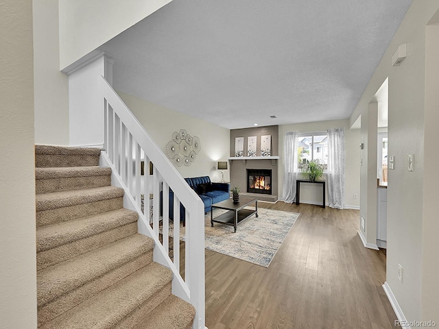 living room with a textured ceiling, a fireplace, and hardwood / wood-style flooring