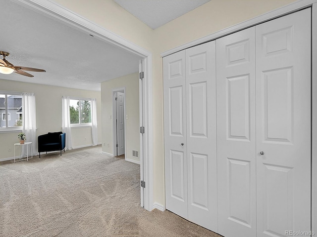 hallway featuring a textured ceiling and light colored carpet