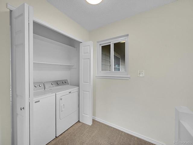 washroom featuring light carpet, a textured ceiling, and washing machine and dryer