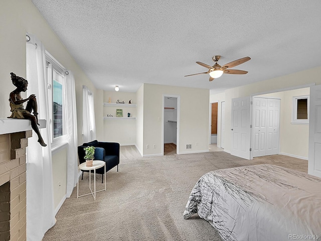 bedroom featuring ceiling fan, a fireplace, a textured ceiling, and light colored carpet