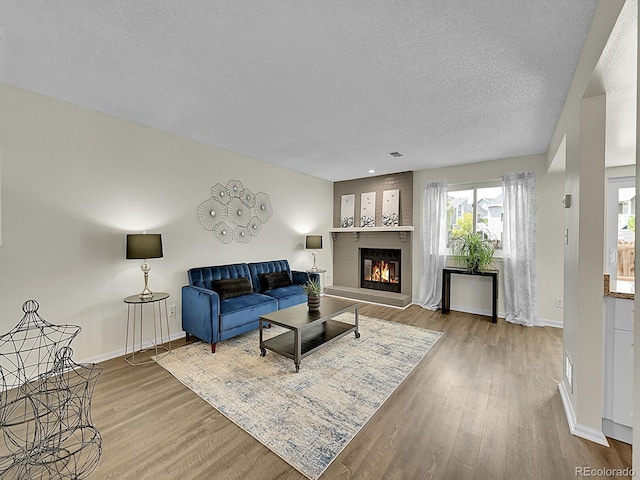 living room with a textured ceiling, a fireplace, and hardwood / wood-style flooring