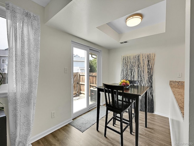 dining space featuring hardwood / wood-style flooring and a raised ceiling