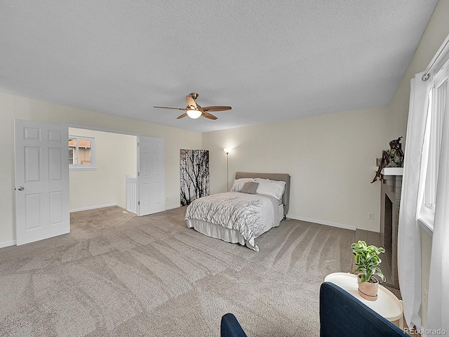 bedroom featuring a brick fireplace, light carpet, a textured ceiling, and ceiling fan