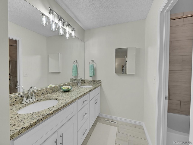 bathroom with vanity, a textured ceiling, and a washtub