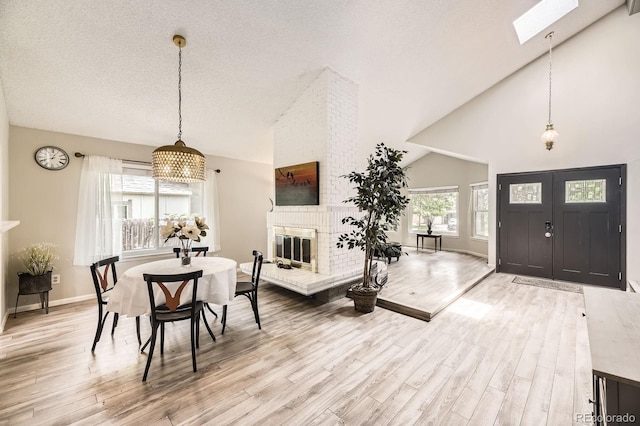 7727 Maroon Peak, Littleton, CO 80127 - dining area featuring a fireplace, wood finished floors, a skylight, high vaulted ceiling, and a textured ceiling
