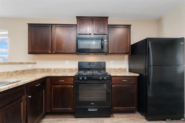 kitchen with black appliances, dark brown cabinets, light wood finished floors, and light countertops