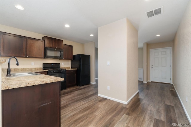 kitchen featuring black appliances, a sink, light countertops, dark brown cabinets, and dark wood-style flooring