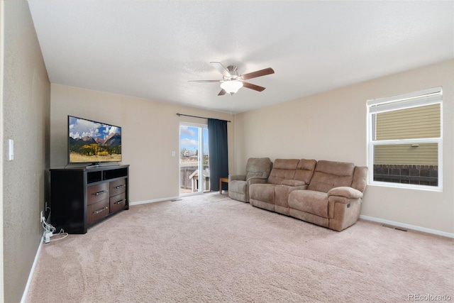 living area with a ceiling fan, light colored carpet, and baseboards