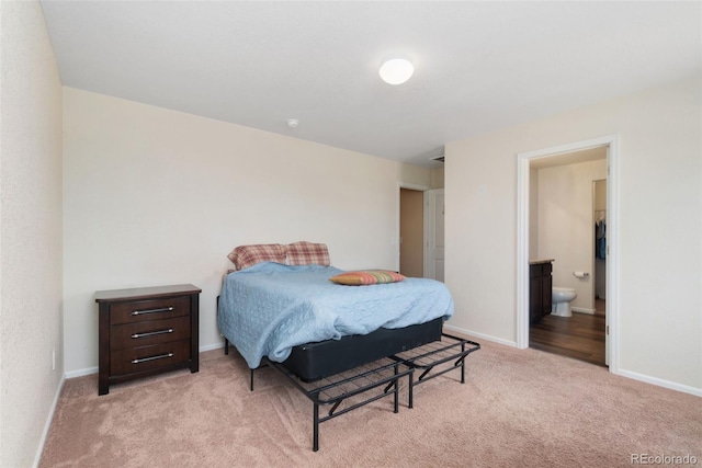bedroom with light carpet, baseboards, and ensuite bathroom