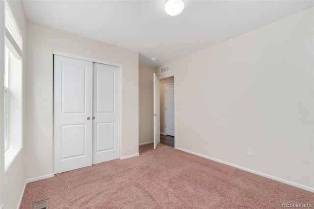 unfurnished bedroom with light colored carpet, a closet, and baseboards