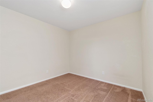 spare room featuring light carpet and baseboards